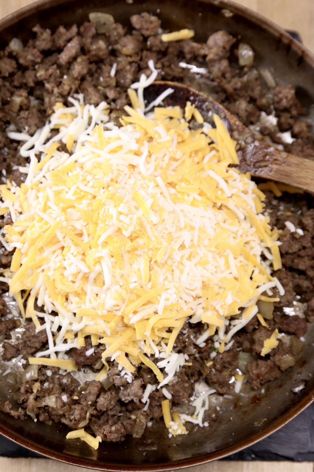 skillet of browned sausage topped with shredded cheese
