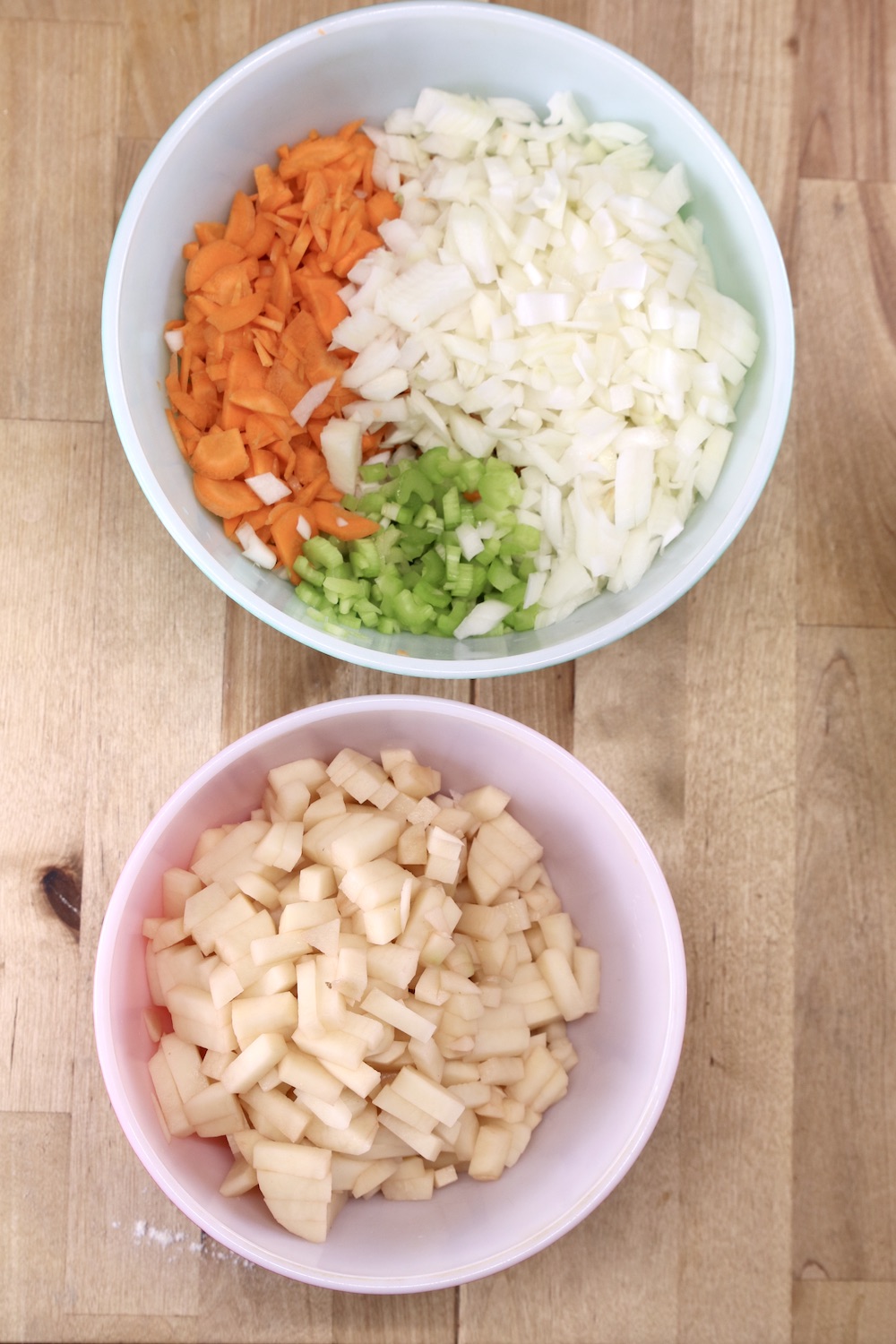 Bowl of diced carrots, celery, onions. Bowl of diced potatoes