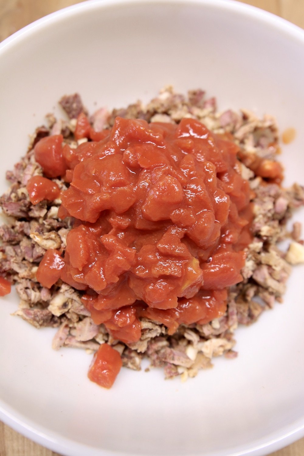 diced tomatoes added to bowl of burrito filling