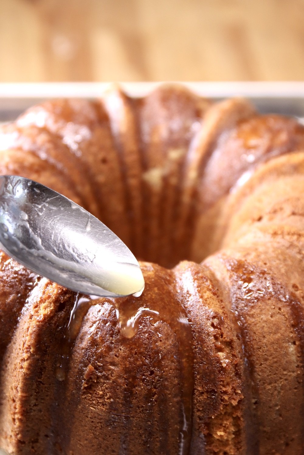 pouring glaze over pound cake with a spoon