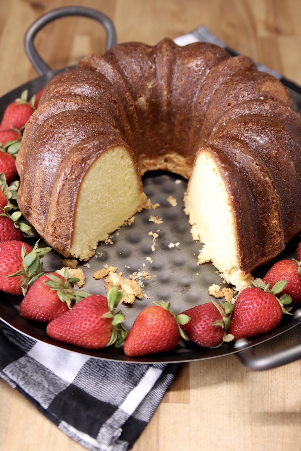 pound cake on a platter, 2 slices removed - strawberries surrounding cake