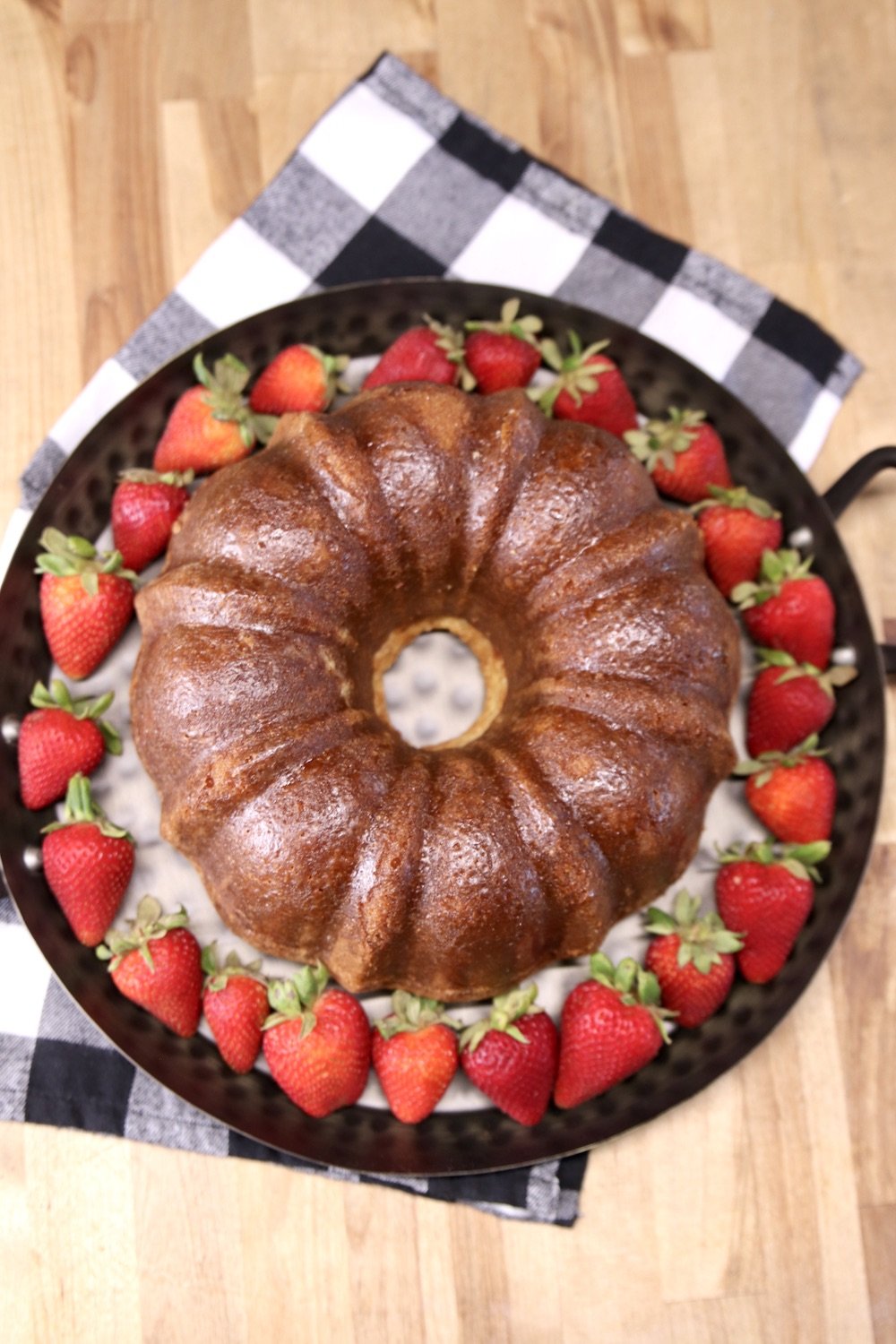 Amaretto pound cake on a tray surrounded with fresh starwberries