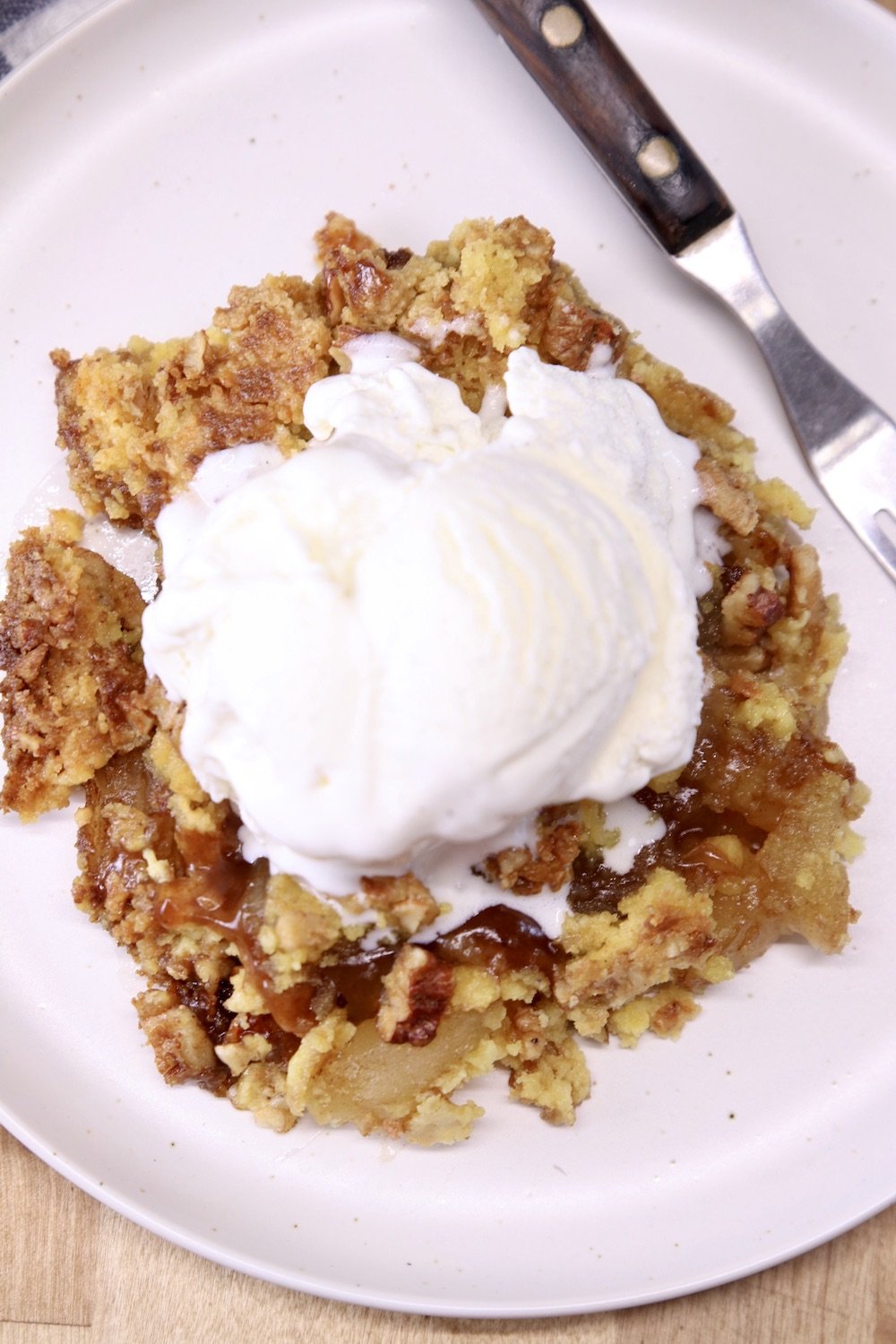 apple dump cake with vanilla ice cream on a plate with a fork