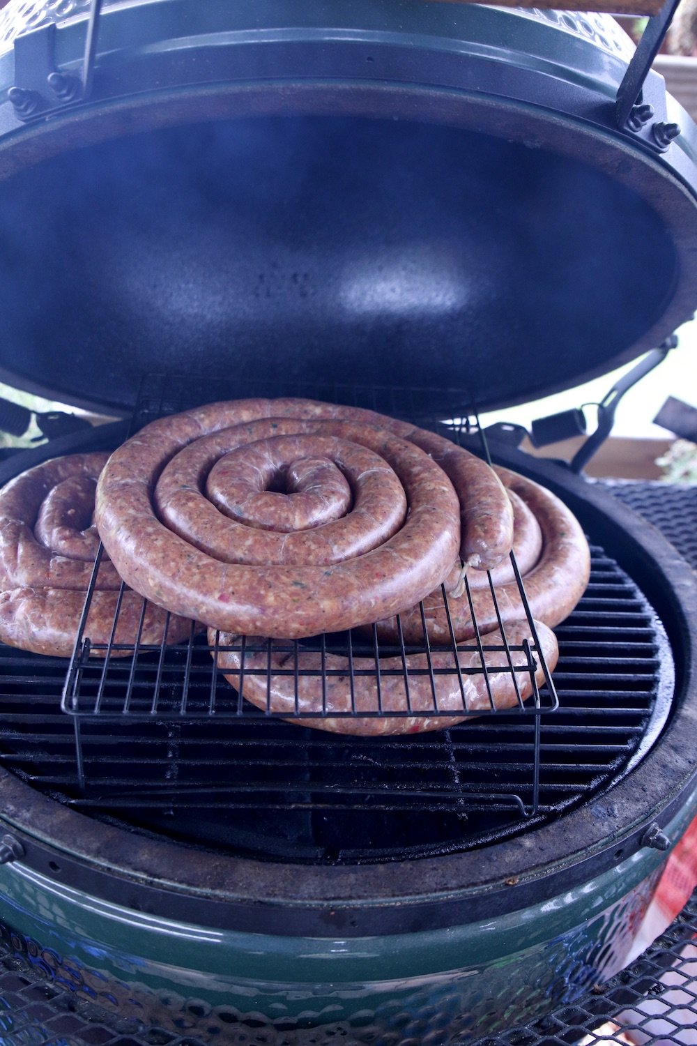 3 spiral smoked sausage links on a grill - stacked with a wire rack