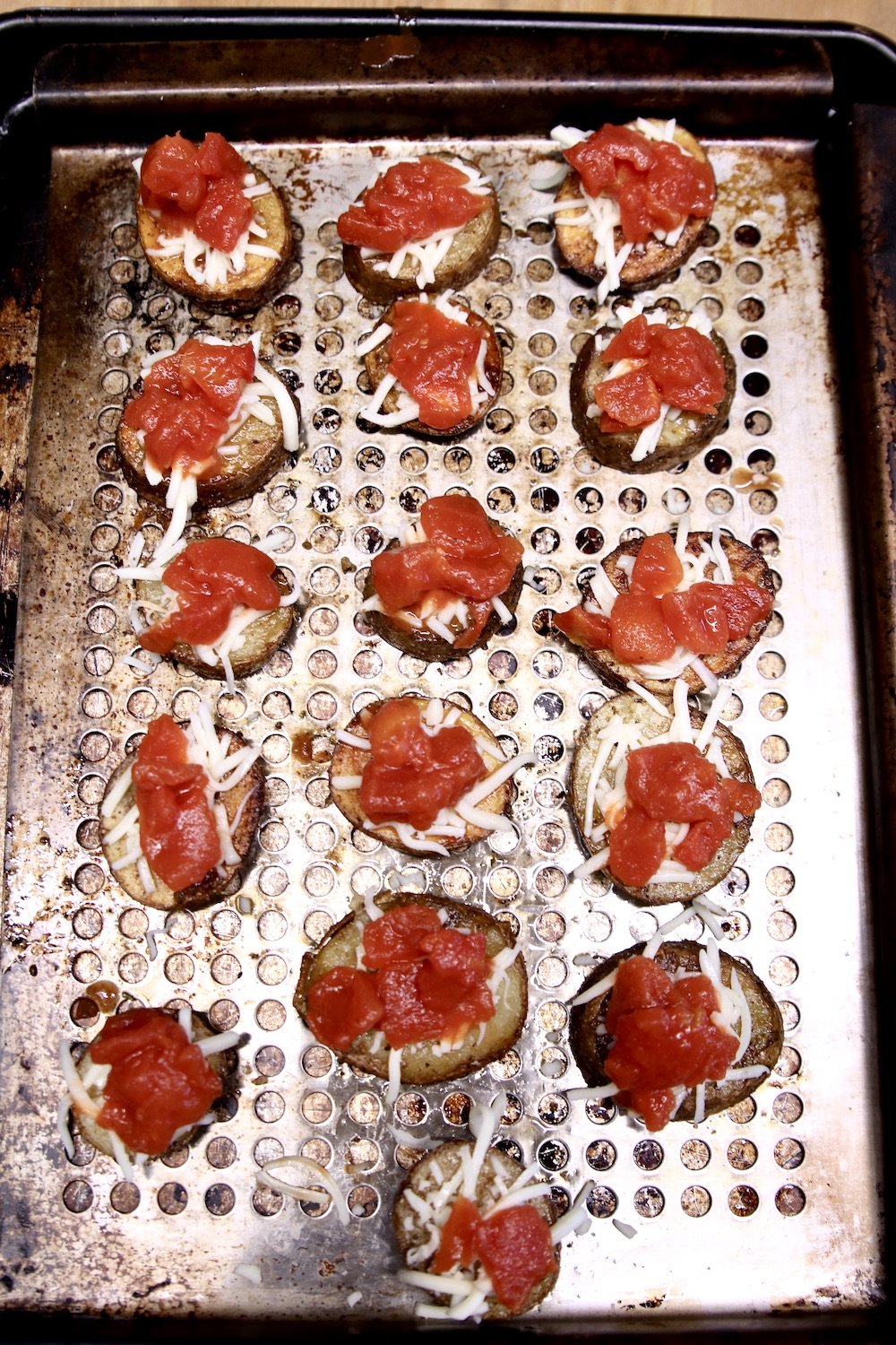 pan of potatoes topped with mozzarella and diced tomatoes