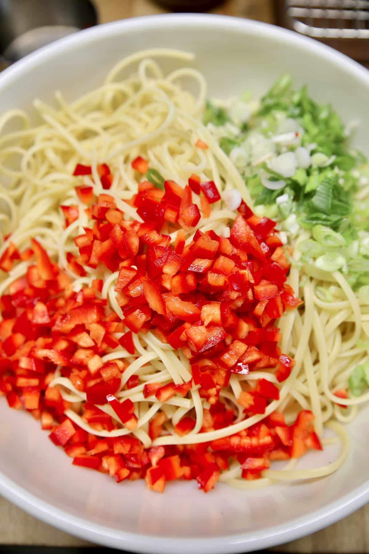 Linguine, green onions and red bell peppers in a bowl.