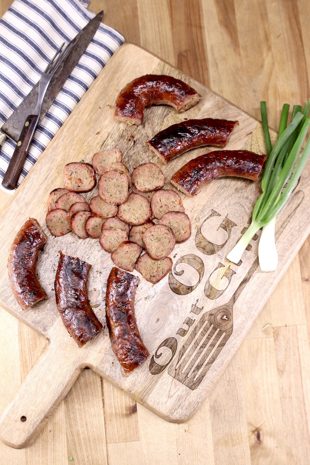 cutting board with smoked sausage links, slices and green onions