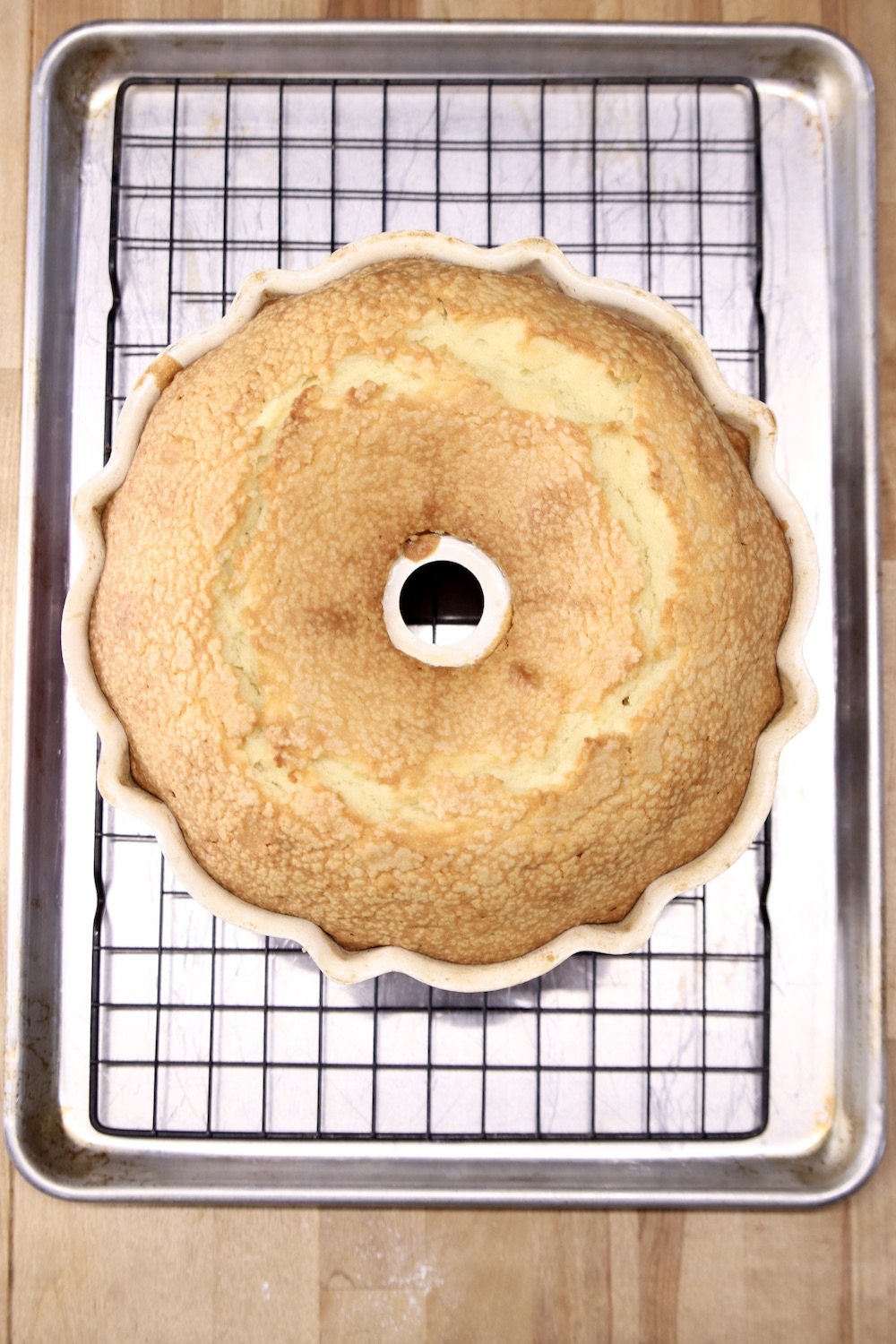 baked pound cake in a bundt pan sitting on a wire rack