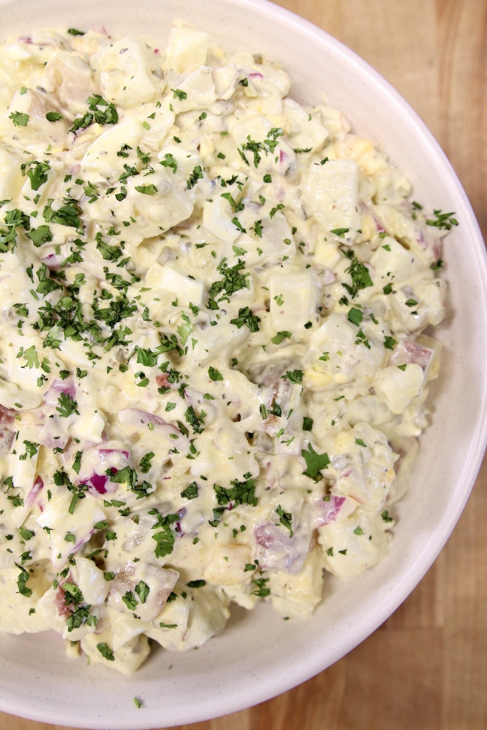 Bowl of potato salad with parsley garnish
