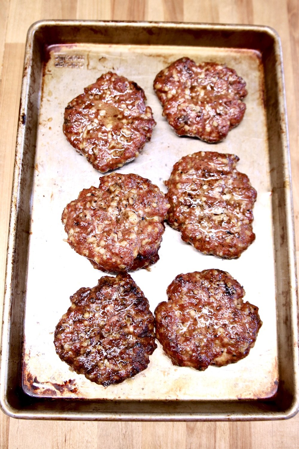 grilled burger patties on a sheet pan