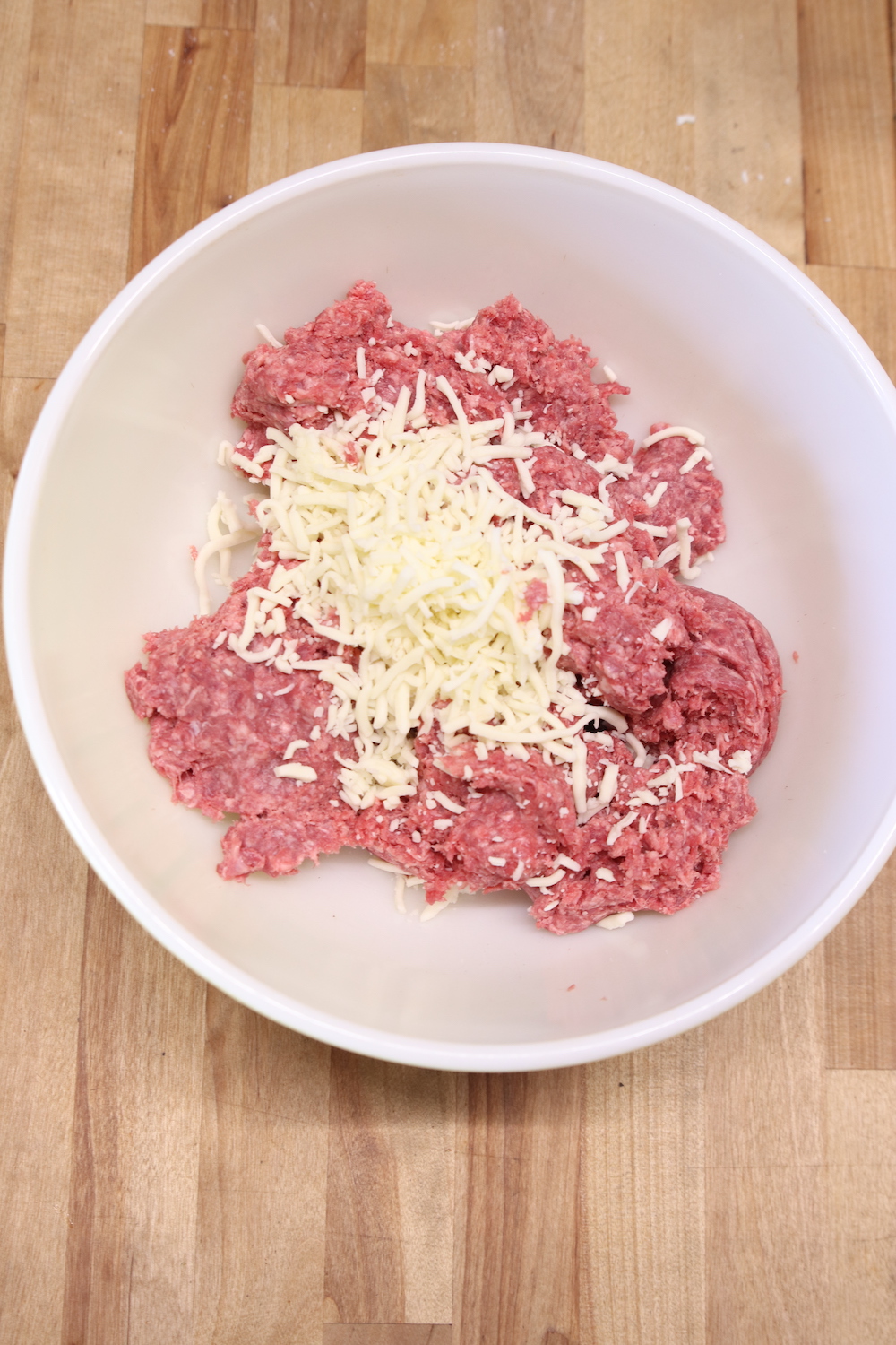 Ground beef in a bowl with shredded mozzarella