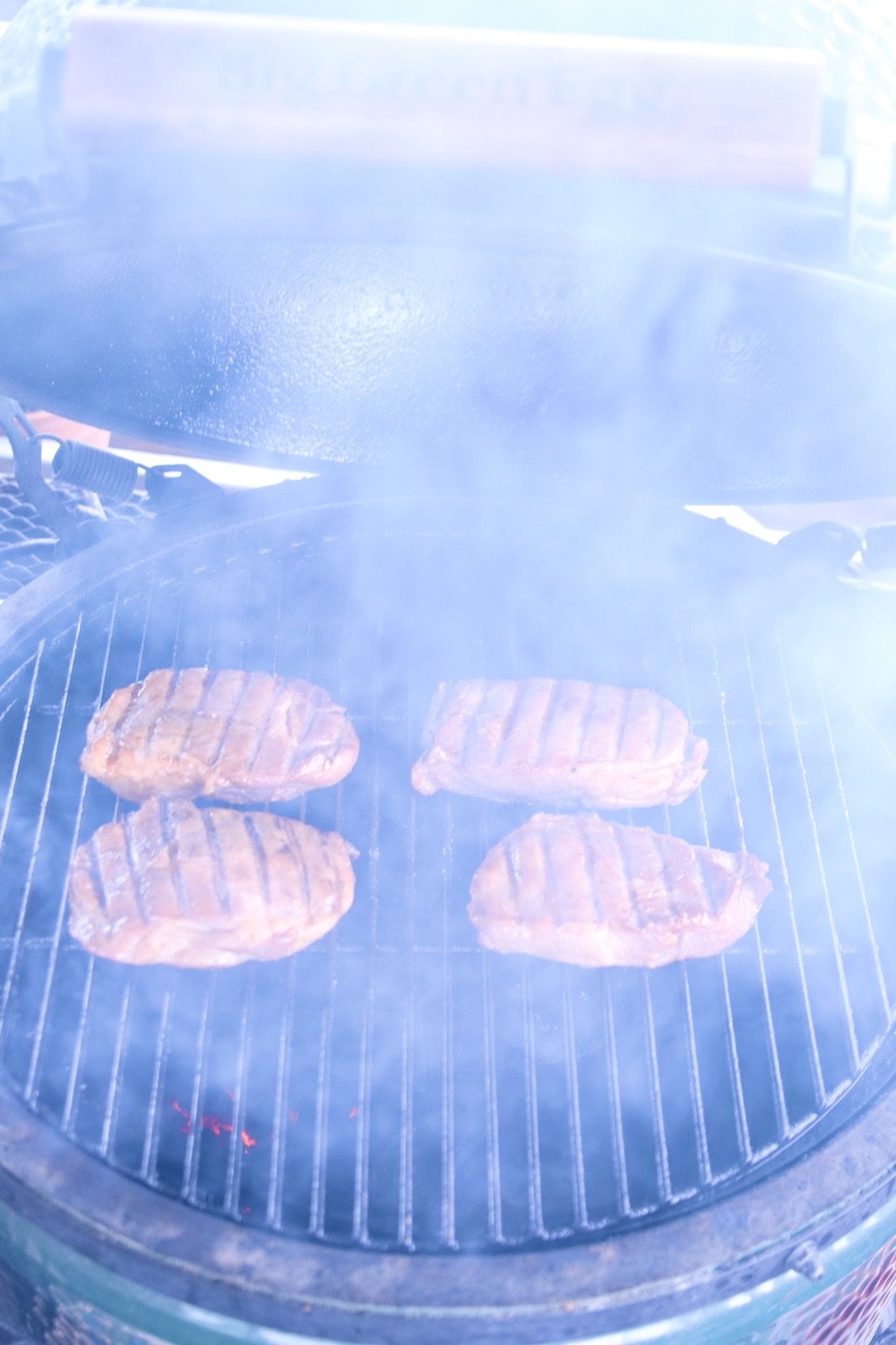 4 pork chops on a grill with smoke