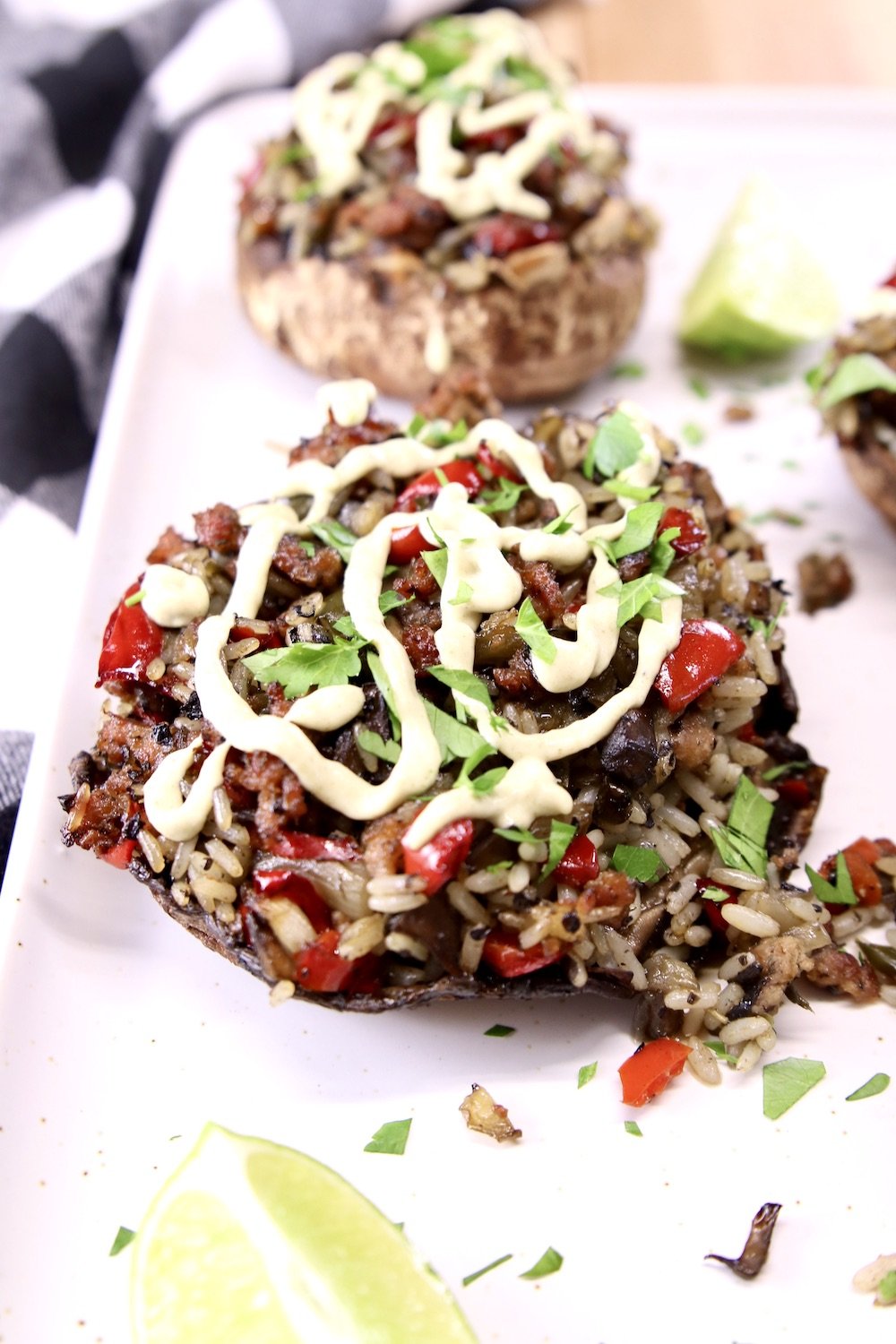 portobello mushrooms on a platter stuffed with sausage, rice and peppers