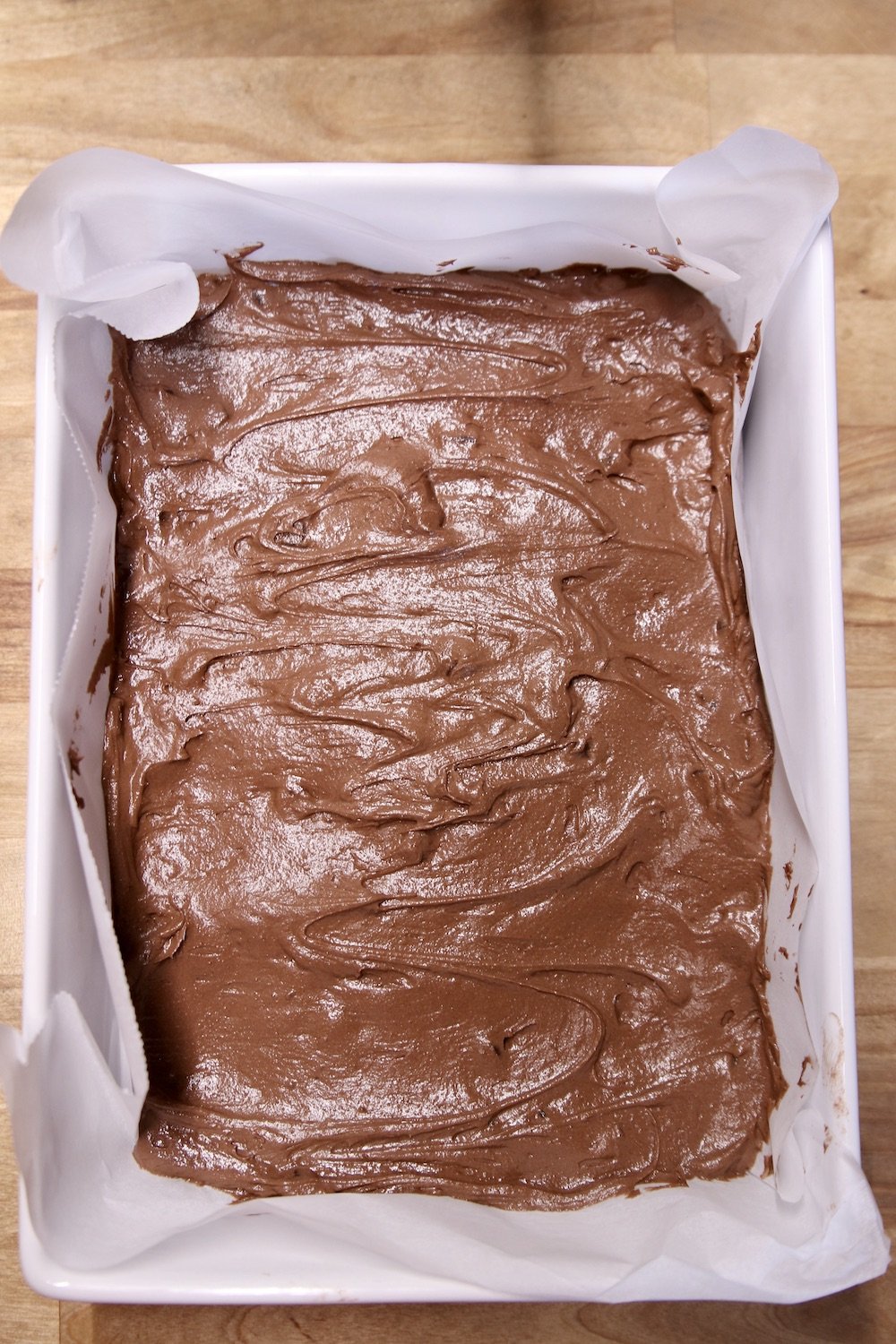 brownie batter spread into a parchment lined baking dish