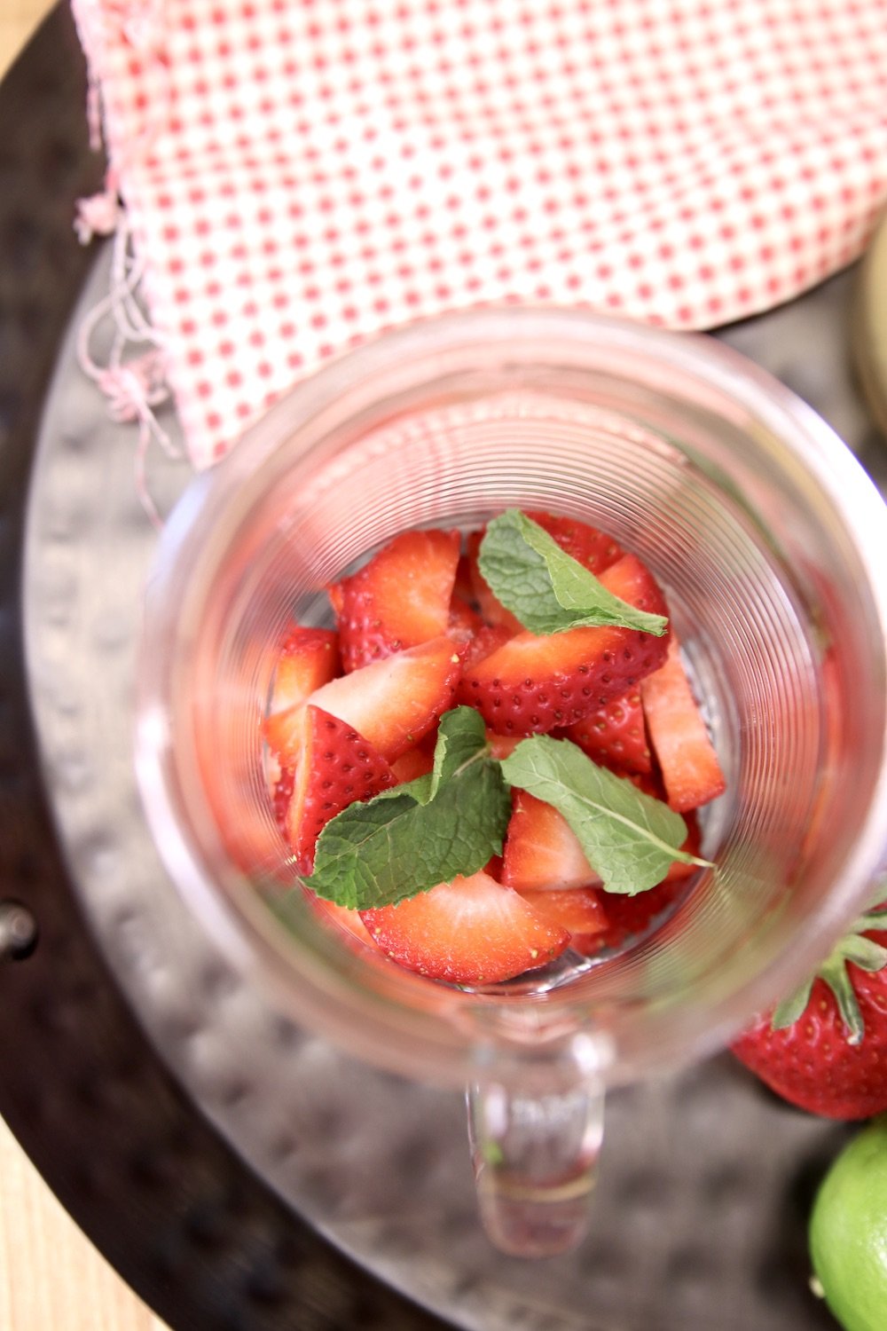 glass with sliced strawberries and fresh mint leaves for a mojito cocktail