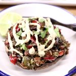 stuffed portobello mushroom with sausage, peppers, rice and cream sauce drizzle