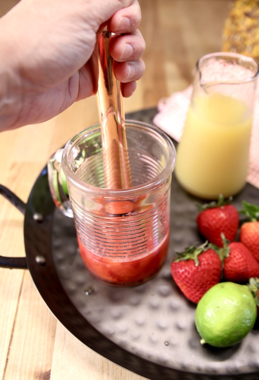 muddling strawberries in a glass for a cocktail