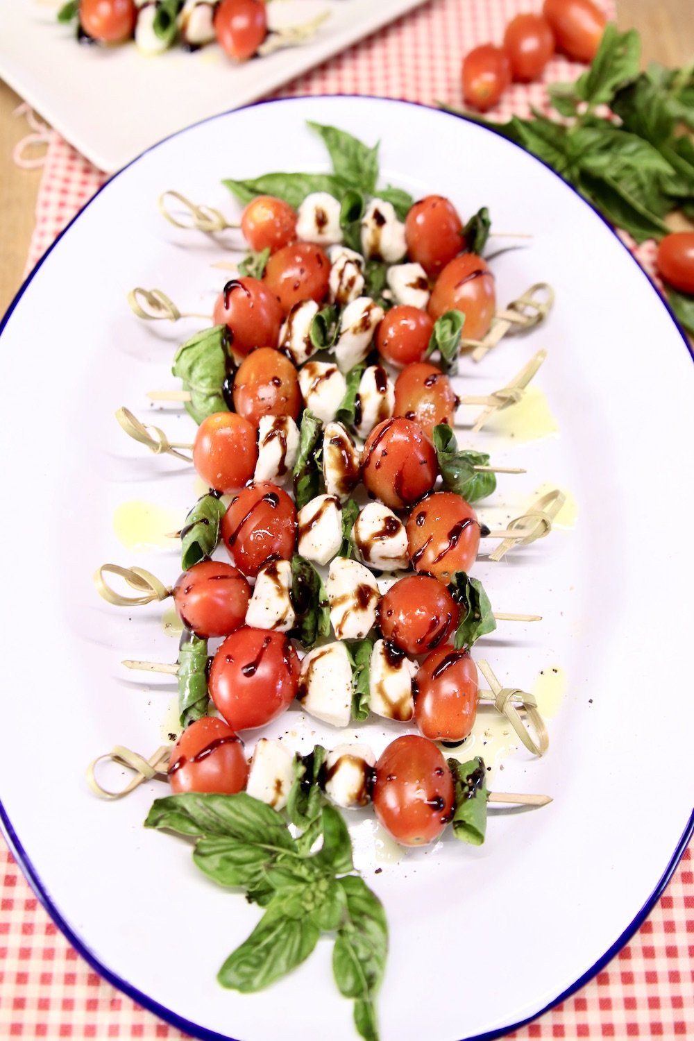 Caprese appetizer picks on a platter with fresh basil