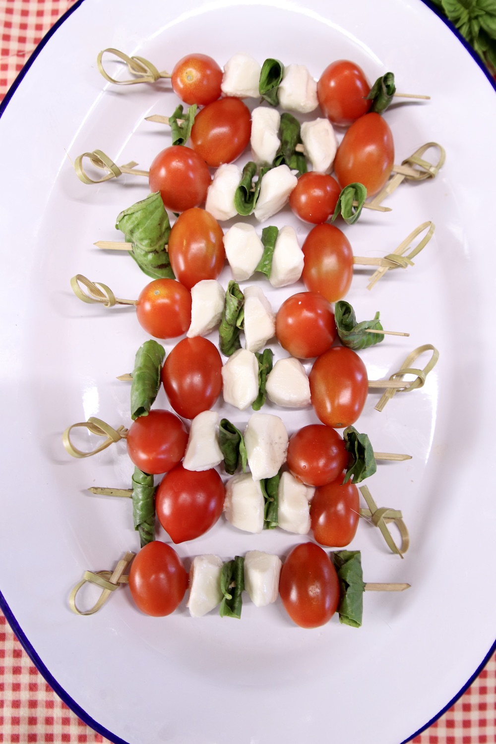 tomato, mozzarella balls and basil on bamboo skewers on a platter