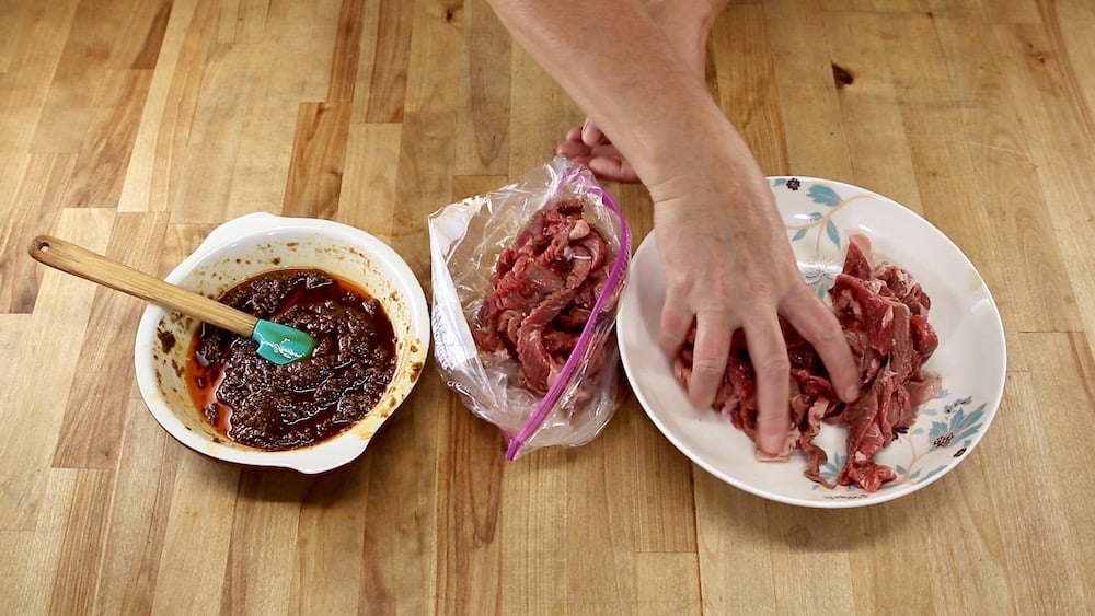 marinade in a bowl, placing thin slices of steak in a baggie for fajitas