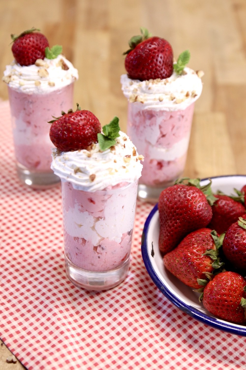 3 dessert glasses with strawberry fluff dessert - topped with cool whip and a strawberry