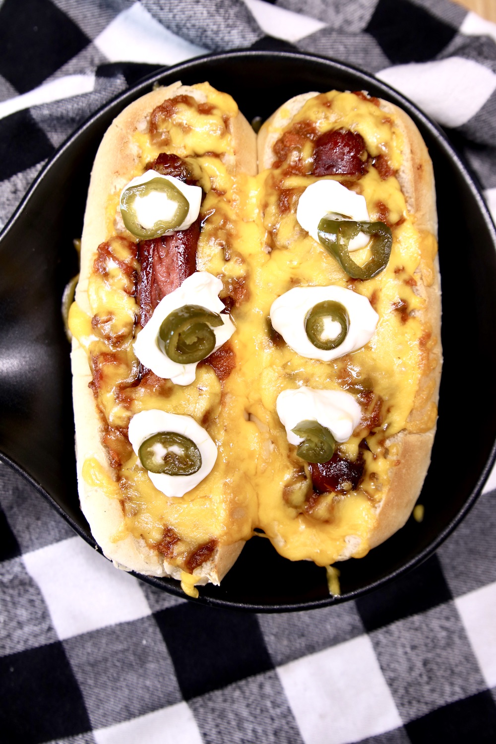 2 chili cheese dogs on a black plate