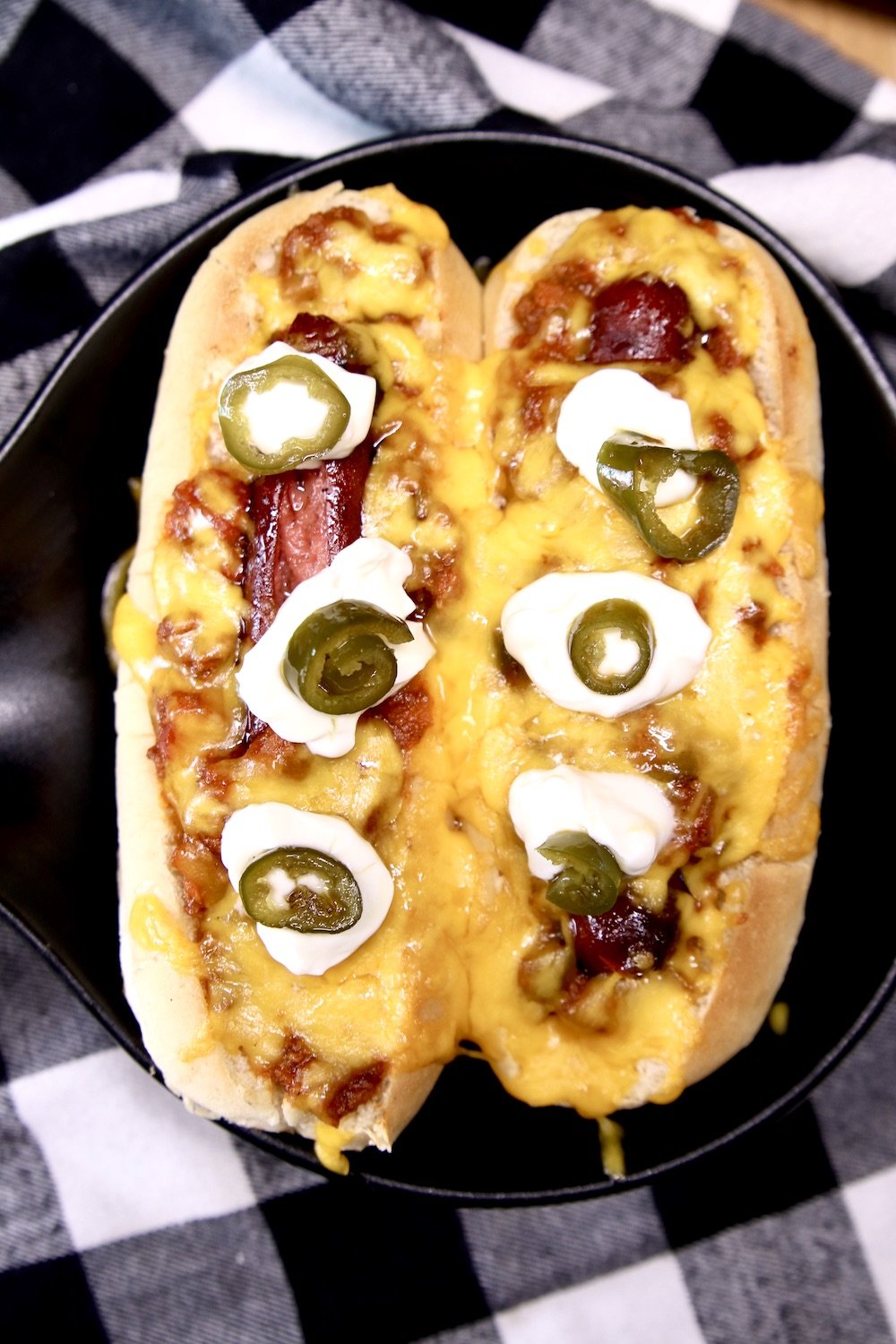 2 chili dogs with sour cream dollops and jalapenos