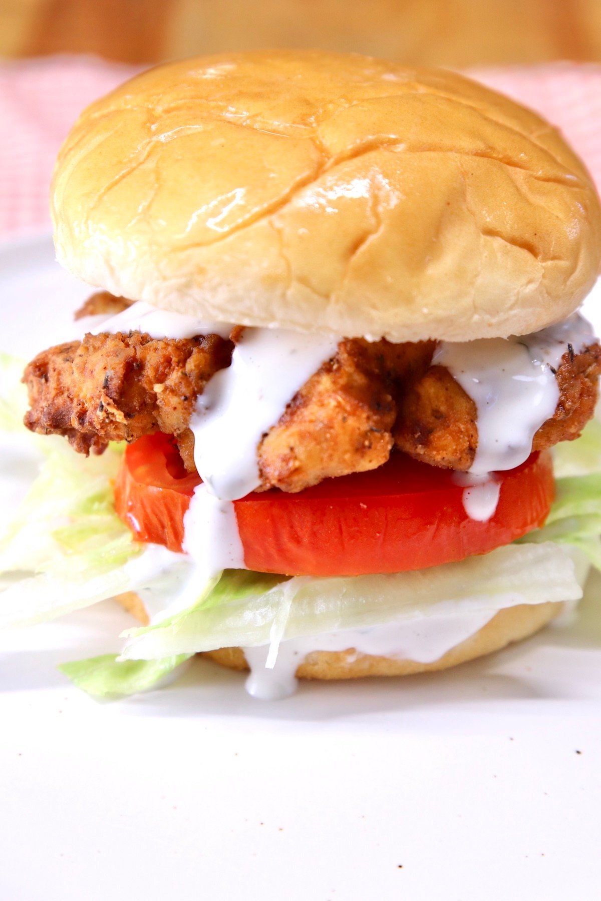 Crispy chicken sandwich with lettuce, tomato and ranch dressing - close up