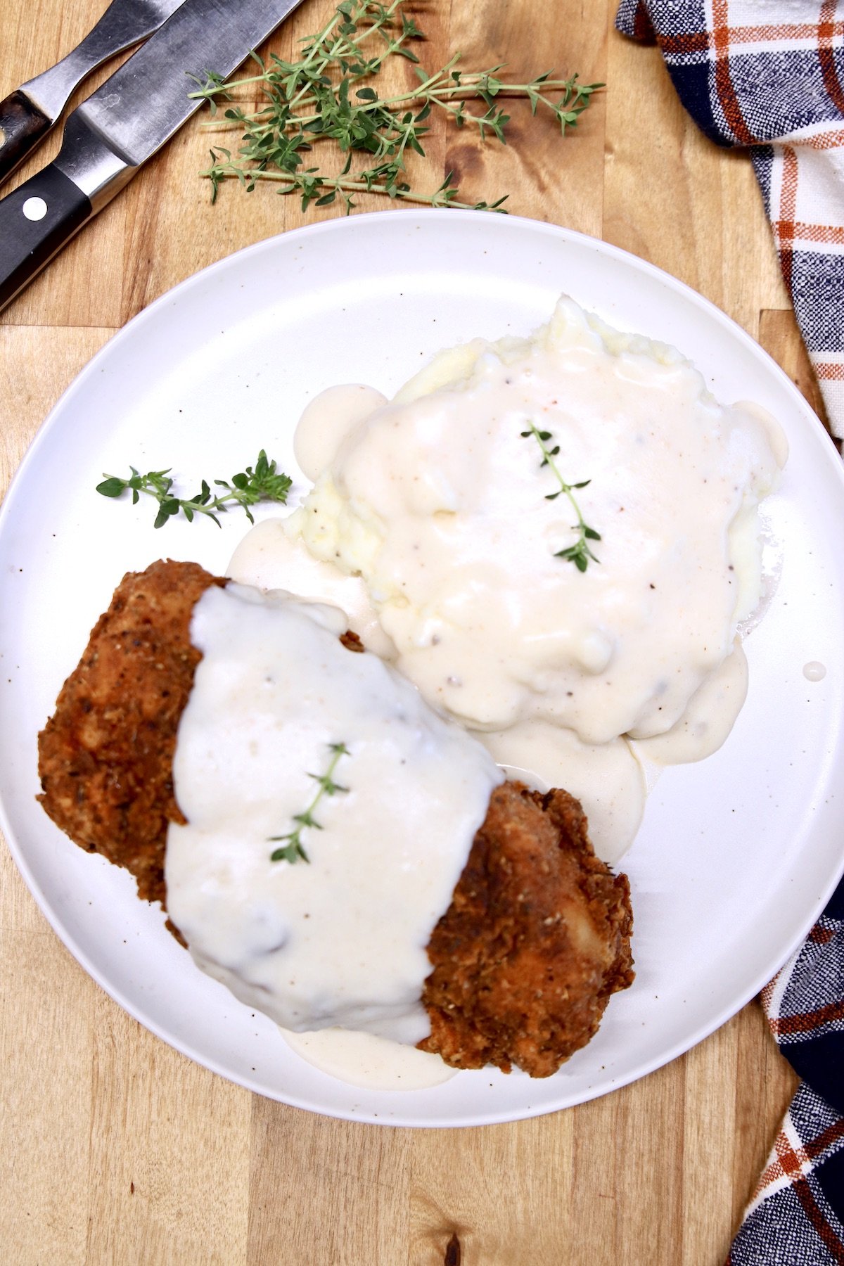 plate with fried pork chop and mashed potatoes, topped with white gravy