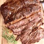 grilled chuck roast on a board, partially sliced