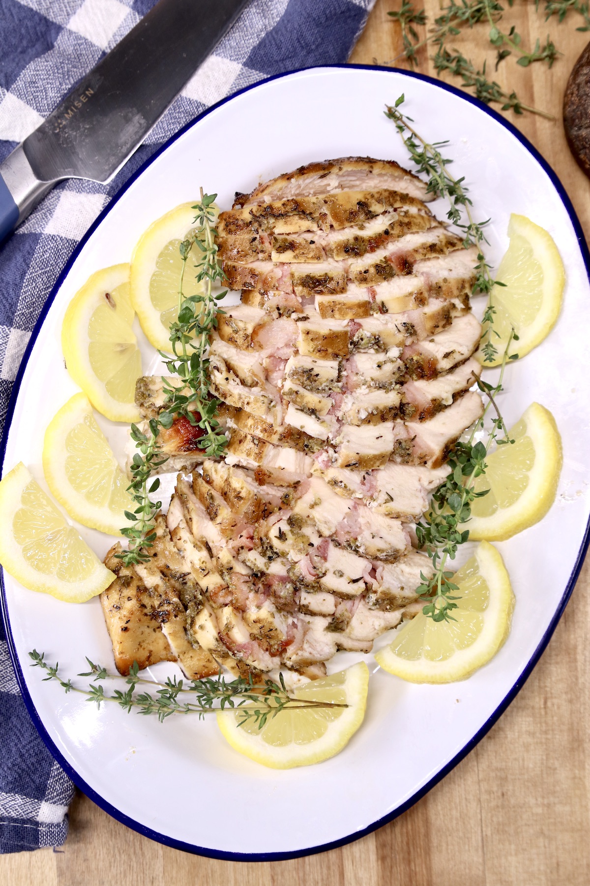 platter of sliced chicken breast with lemon and thyme garnish
