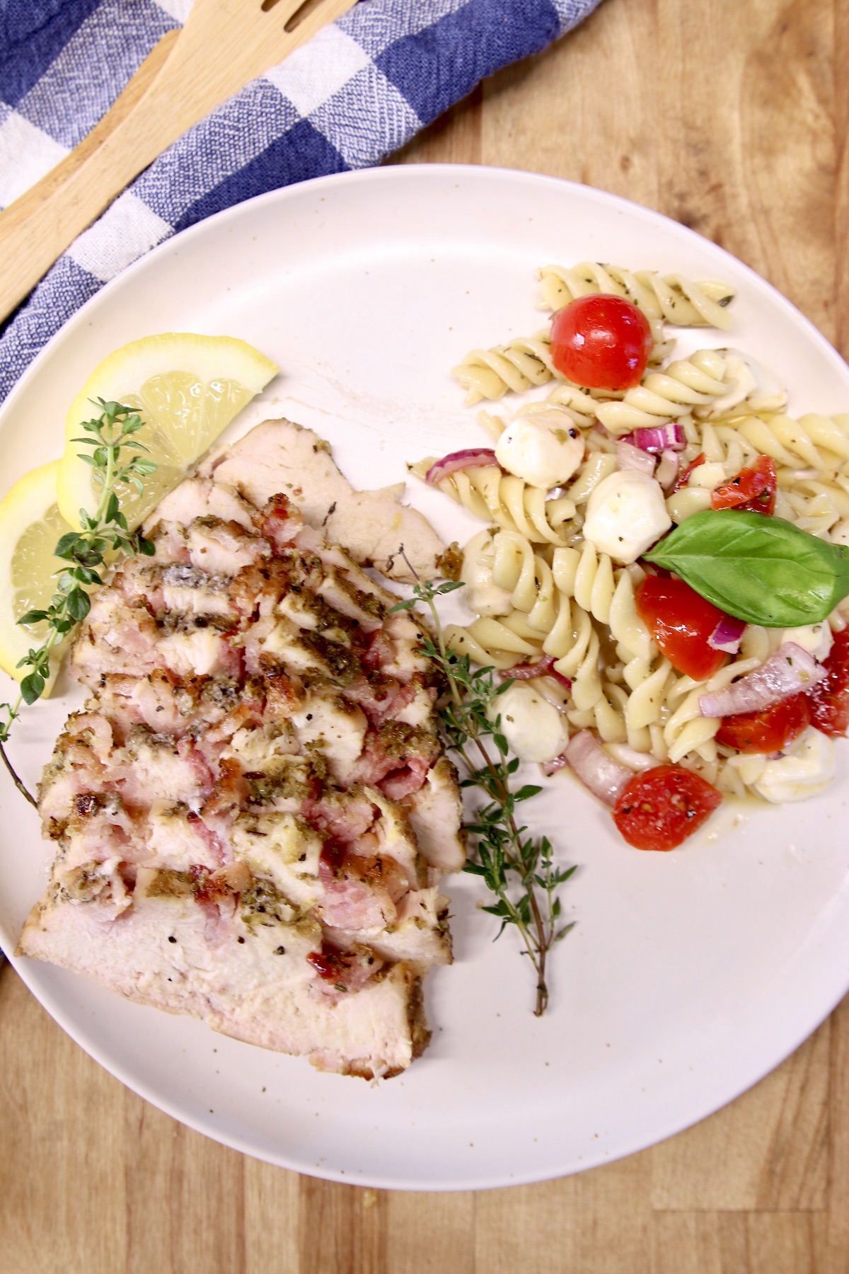 plate of sliced chicken and pasta salad with tomatoes, mozzarella and basil