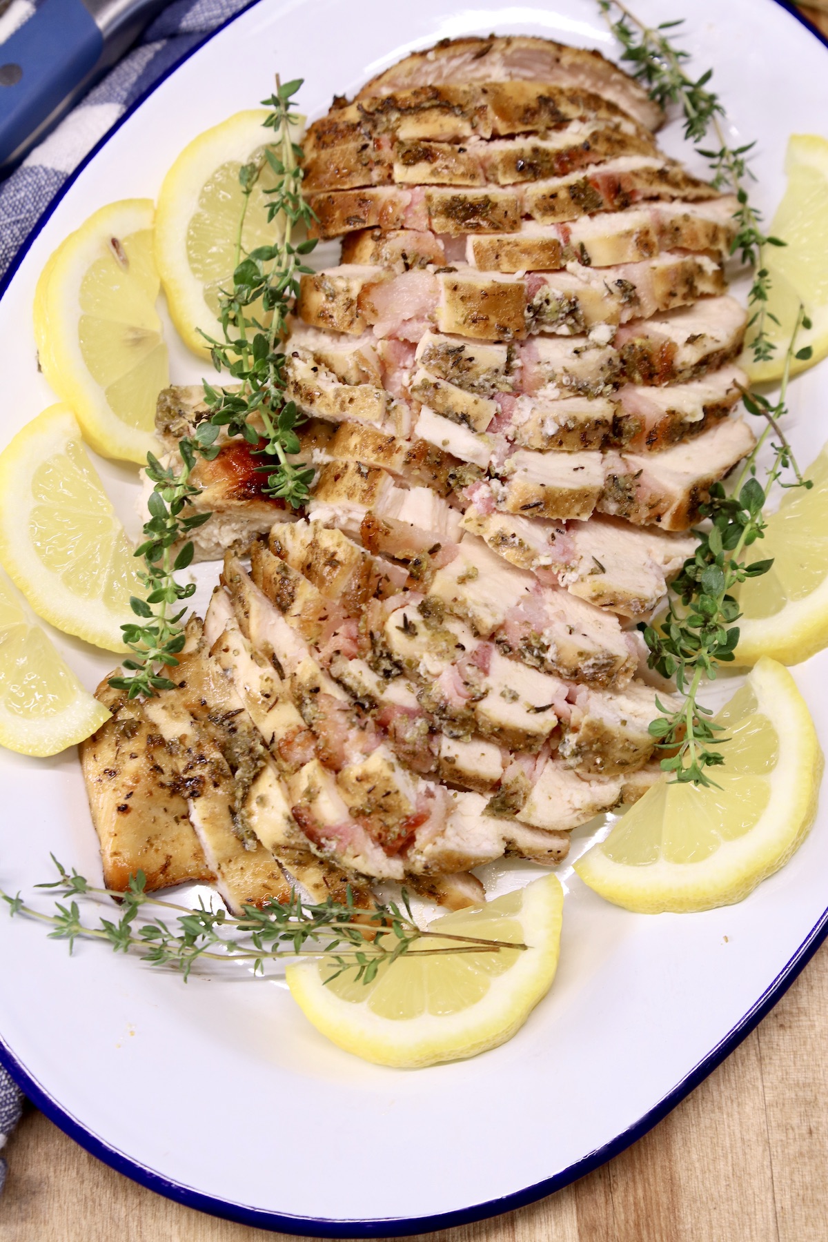Platter of sliced chicken with lemon and thyme garnish