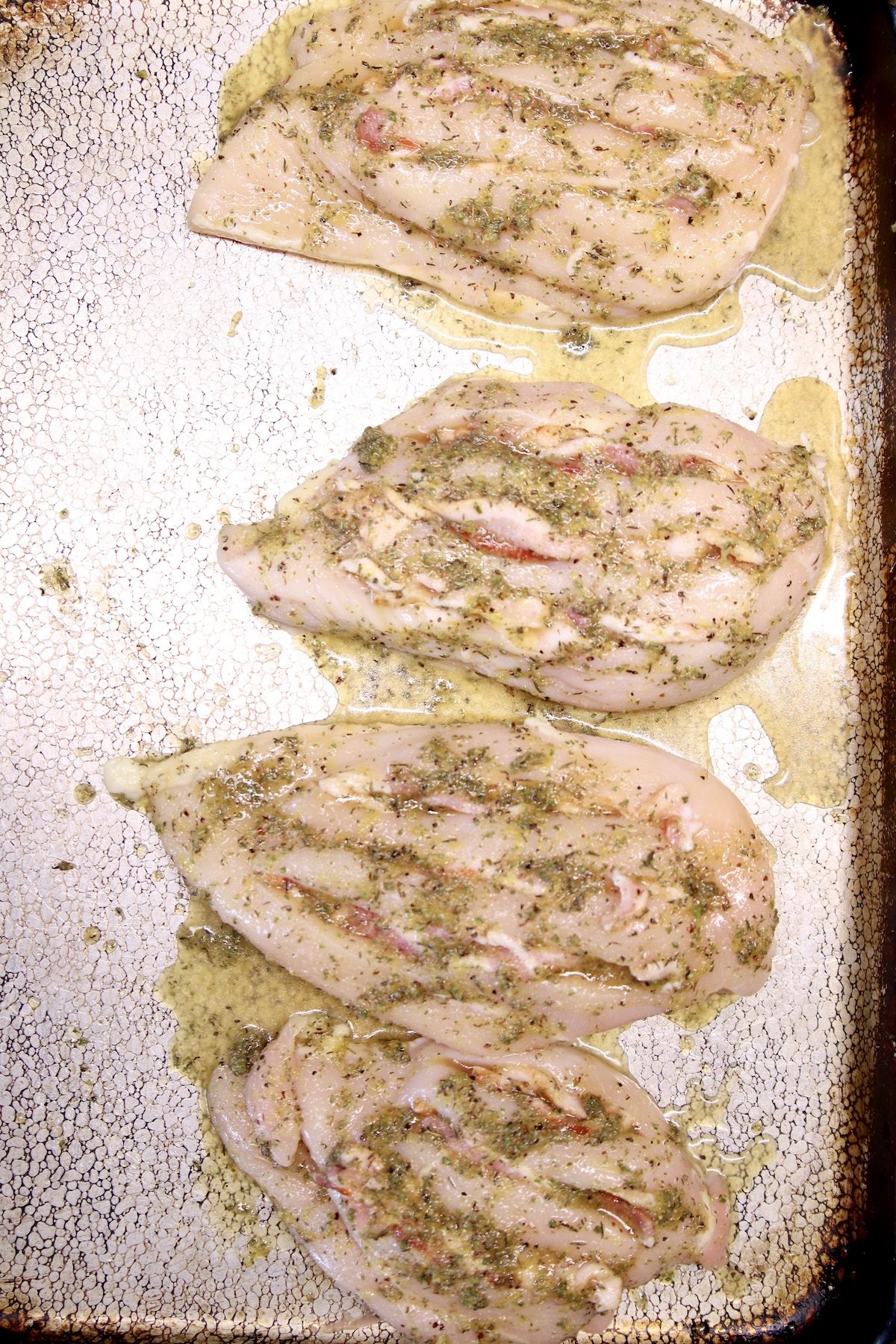 sheet pan with 4 chicken breasts, stuffed with bacon and topped with marinade