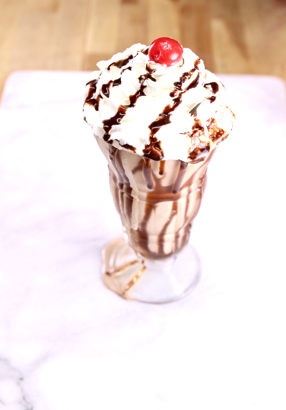 chocolate shake with whipped cream, chocolate drizzle and a cherry 