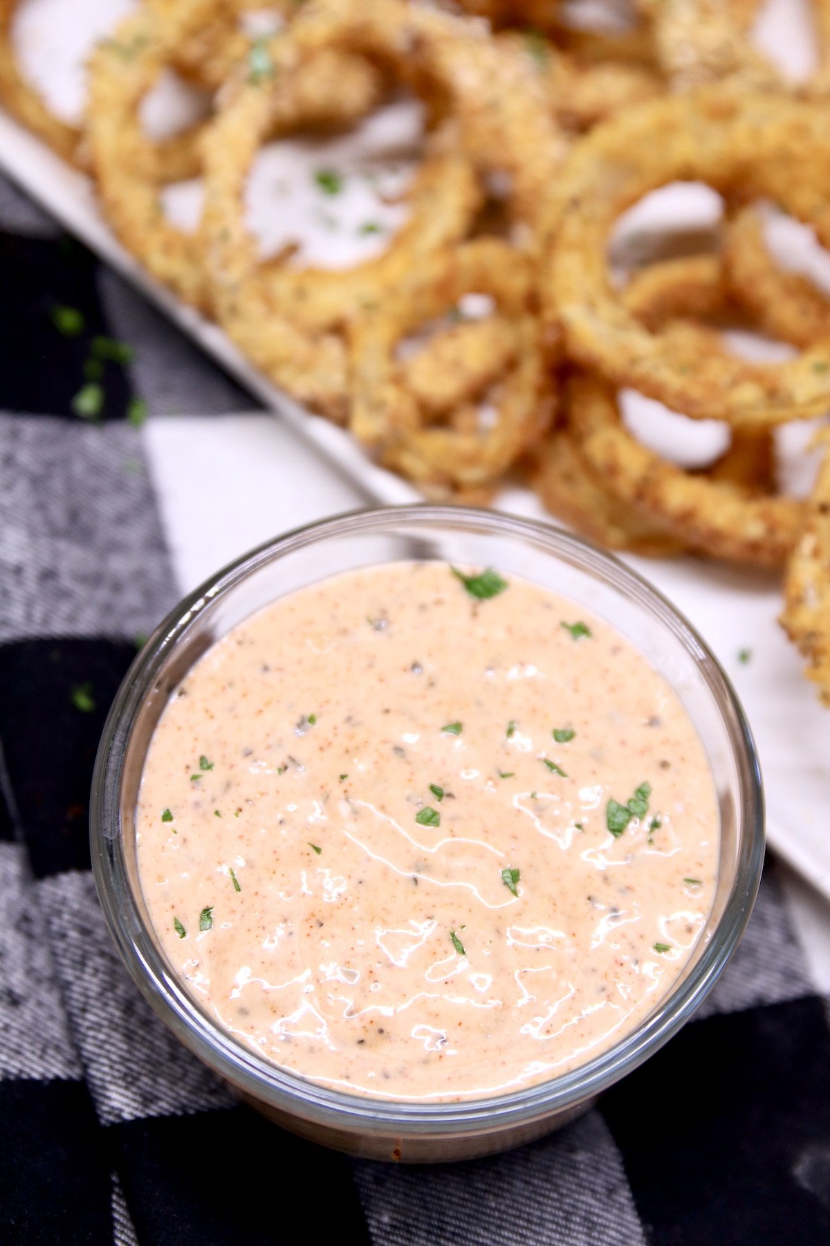 blooming onion sauce in a small bowl with platter of onion rings