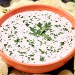 Caramelized Onion Dip in an orange bowl topped with chopped parsley