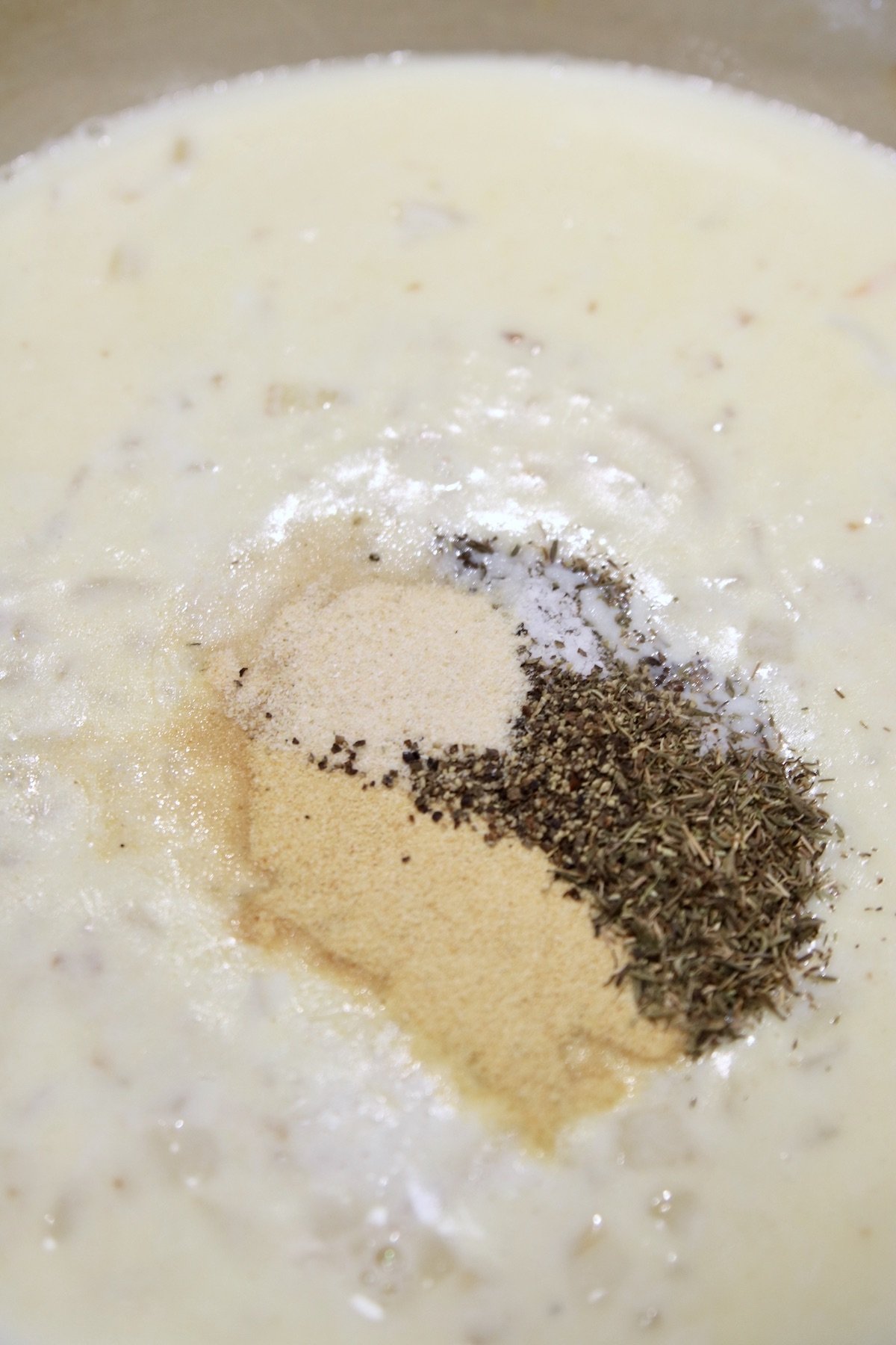 spices added to creamy sauce in a pan