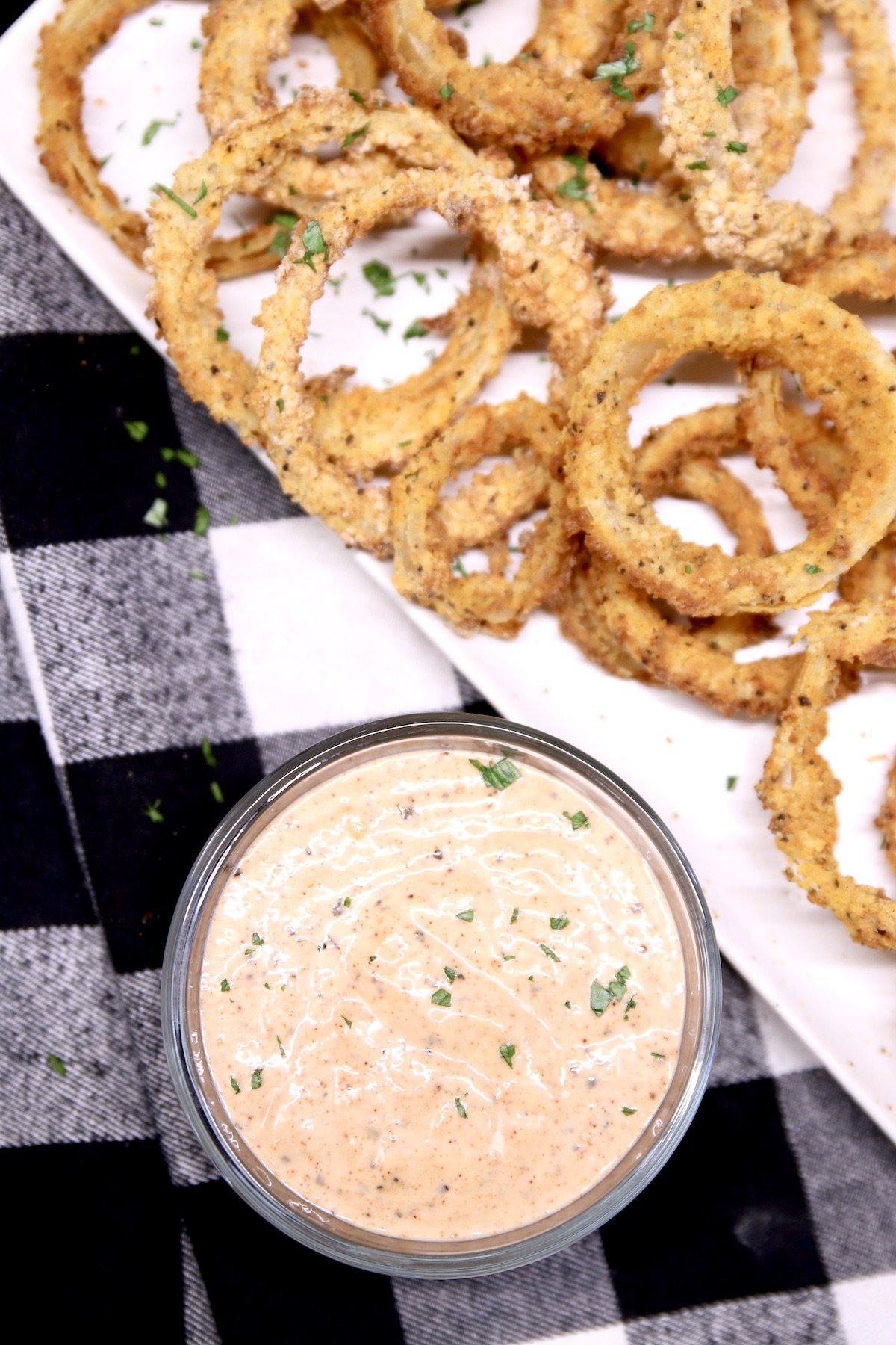 Onion rings on a platter with dipping sauce in a bowl