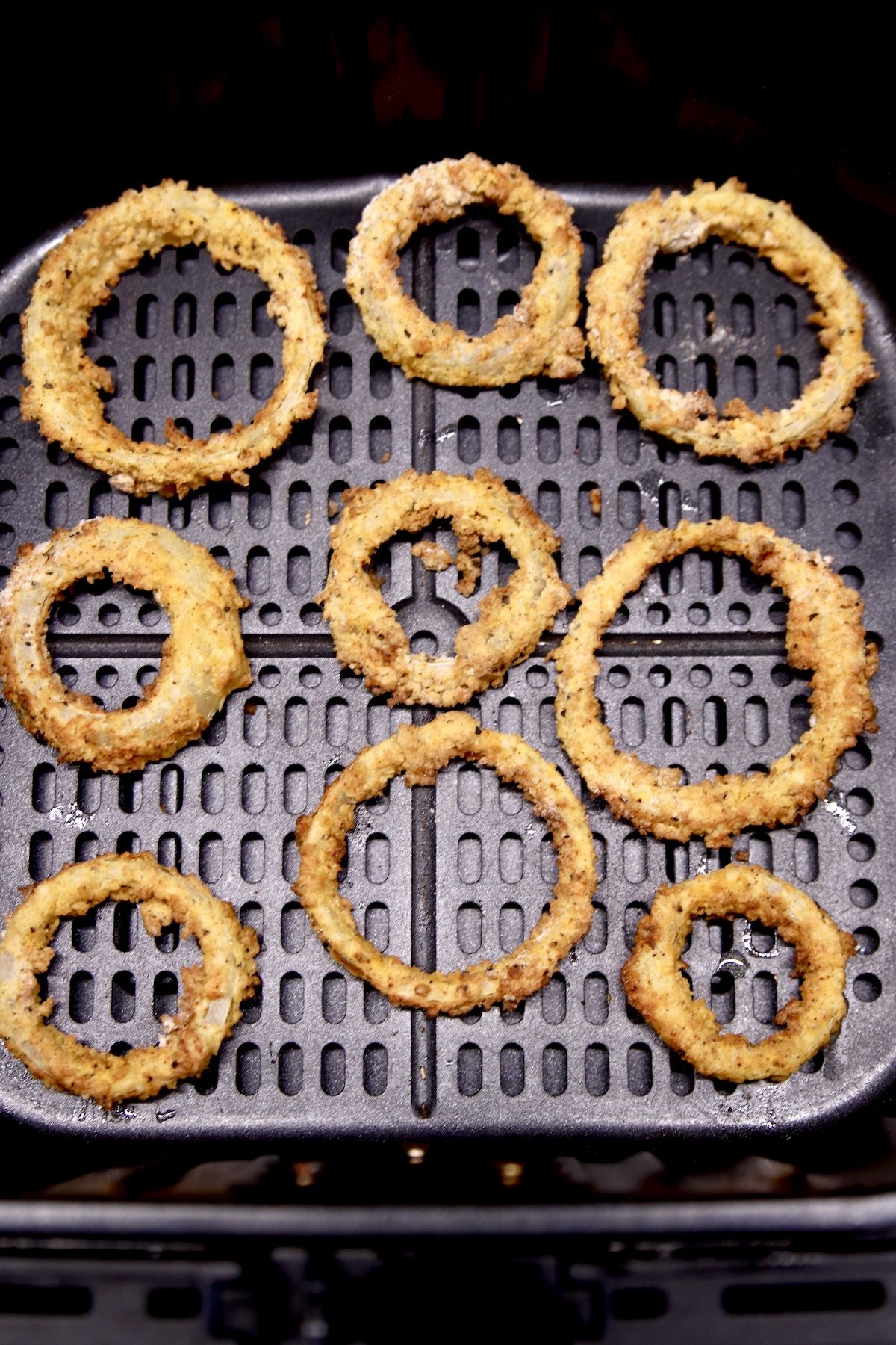 air fryer basket with golden brown onion rings
