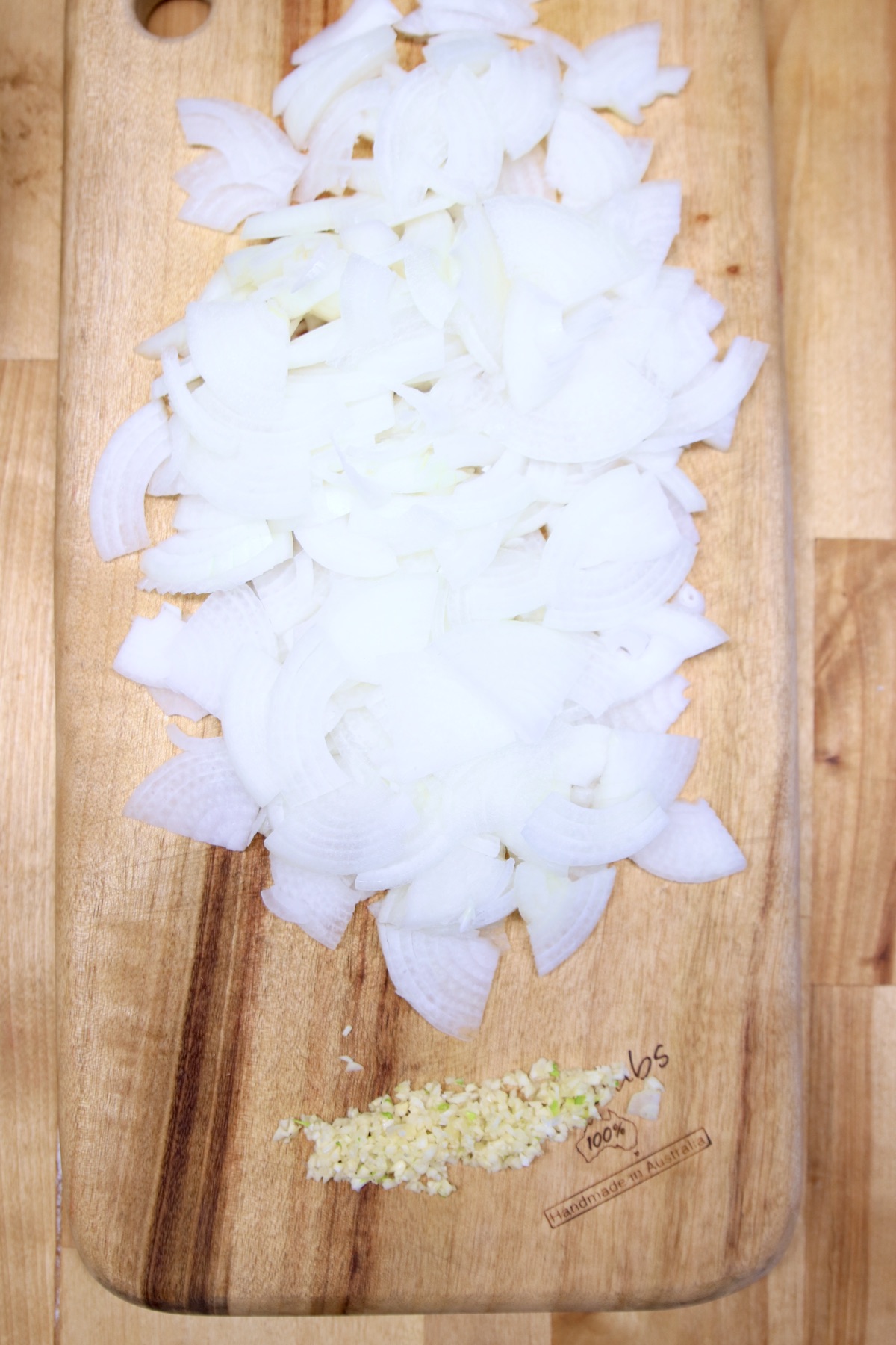 cutting board with sliced onion and minced garlic