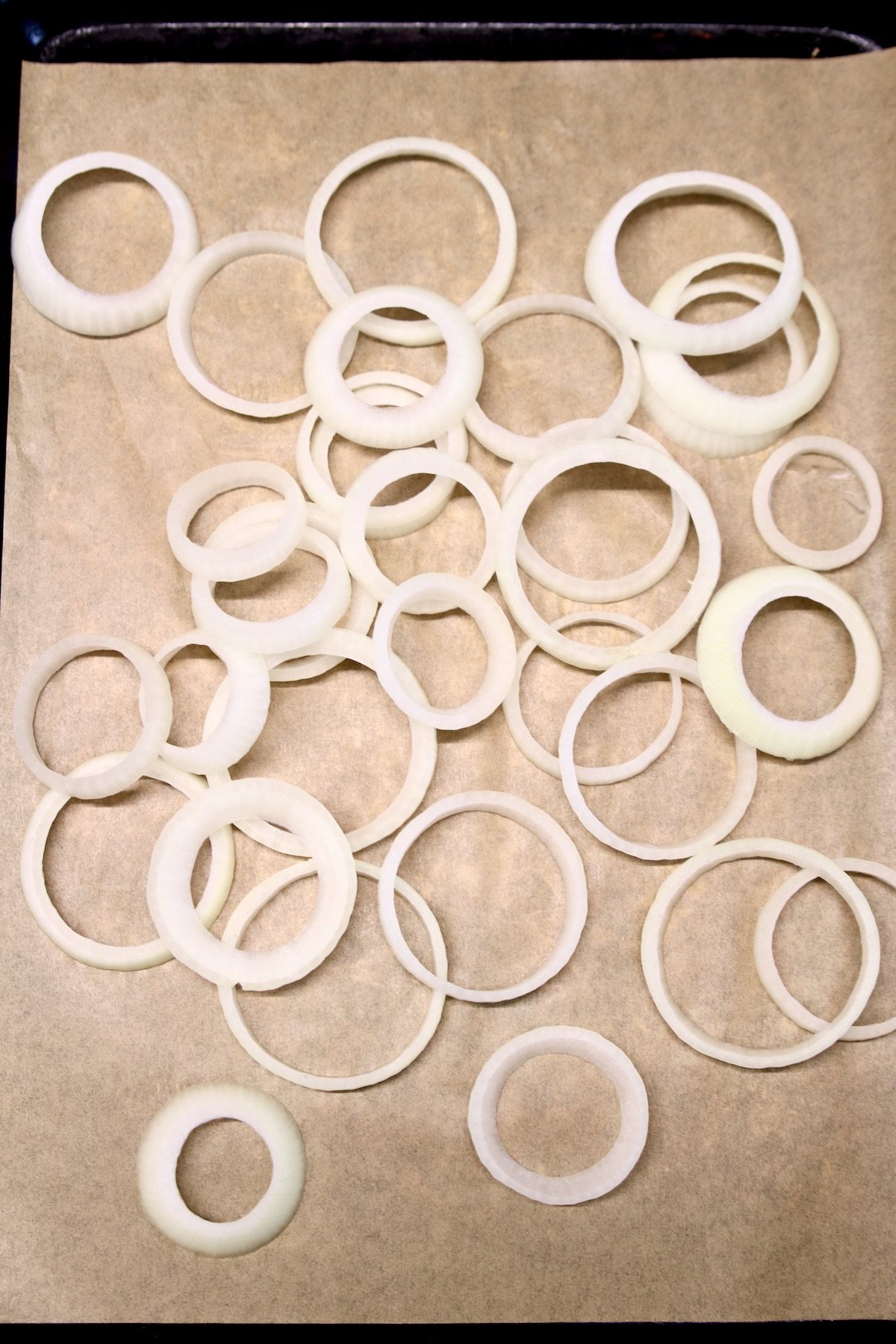 sliced onions on a parchment lined baking sheet