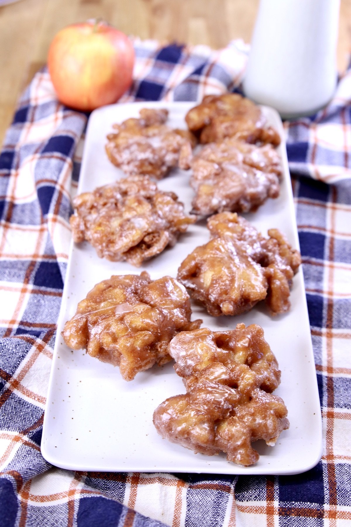 apple fritters on a tray with an apple and milk to the side