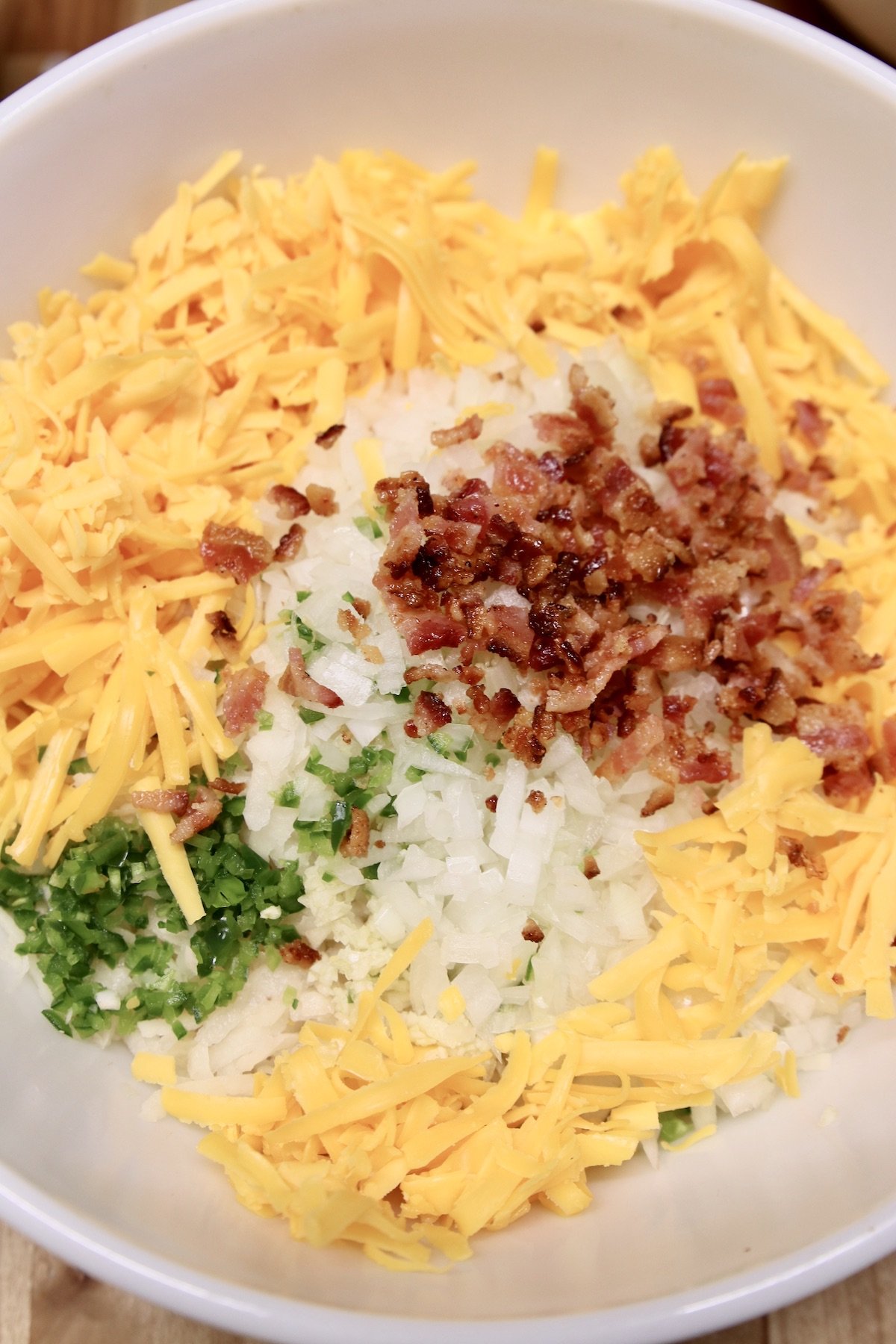 hashbrown casserole ingredients in a bowl, cheese, jalapeno, bacon