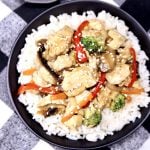 chicken stir fry over rice in a black bowl