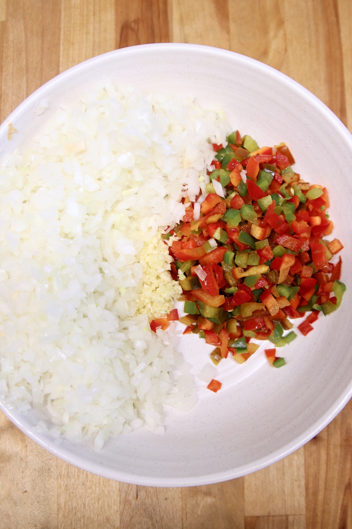 bowl of diced onions, minced garlic, diced red and green bell peppers