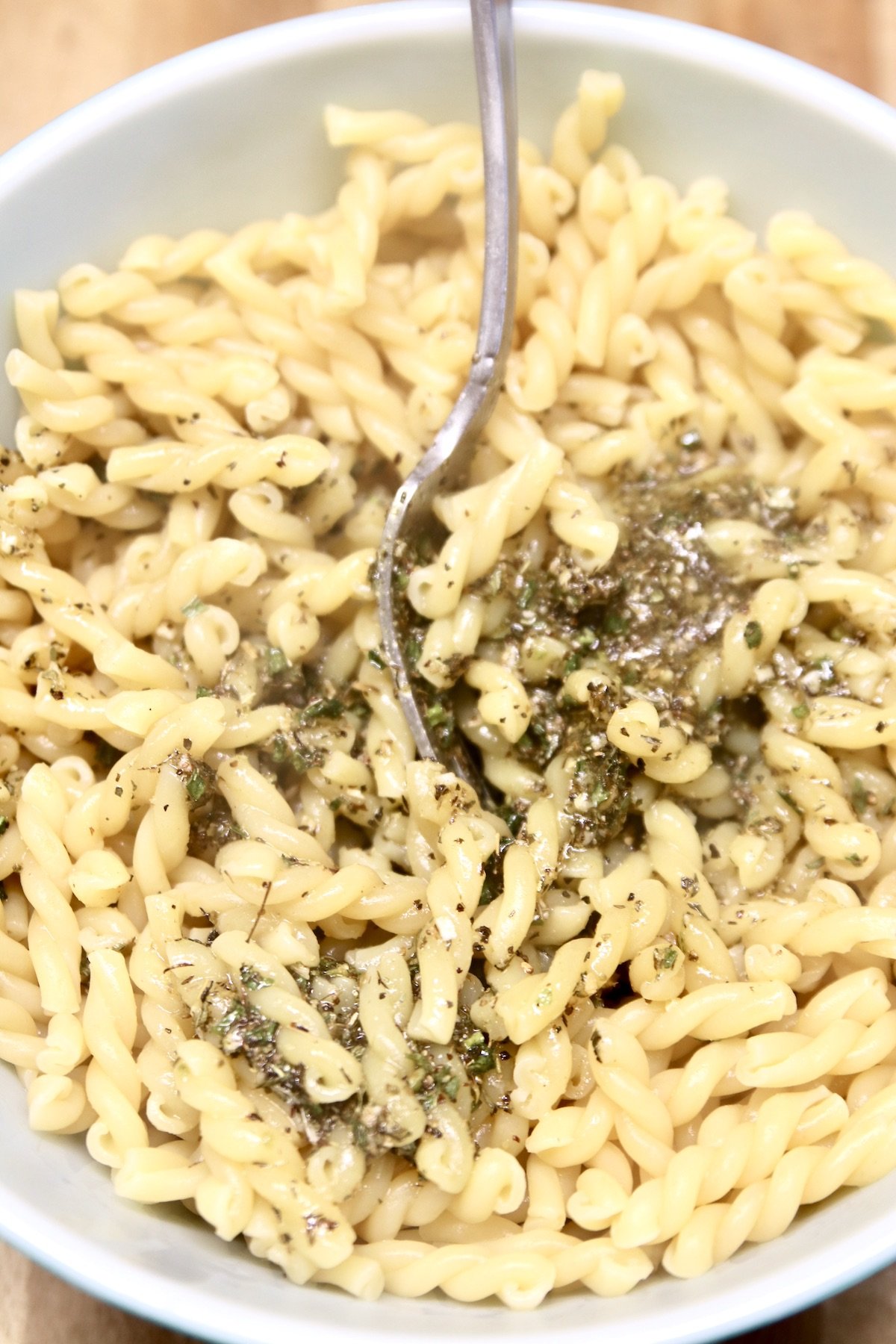 bowl of pasta with herb dressing poured over the top