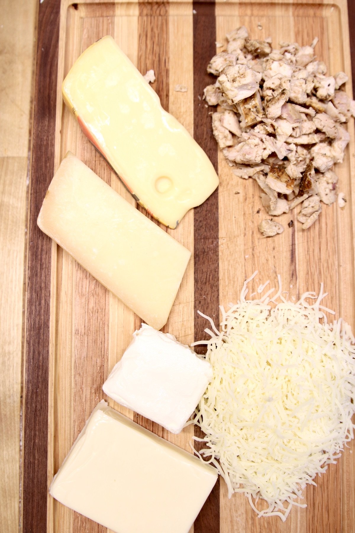 cutting board with 5 kinds of cheese, smoked chicken, diced
