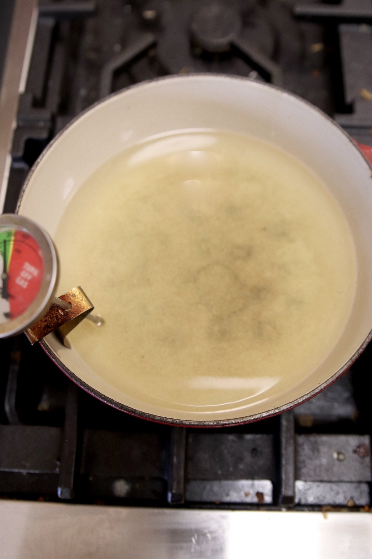 vegetable oil heating in a pan on the stove with a oil thermometer