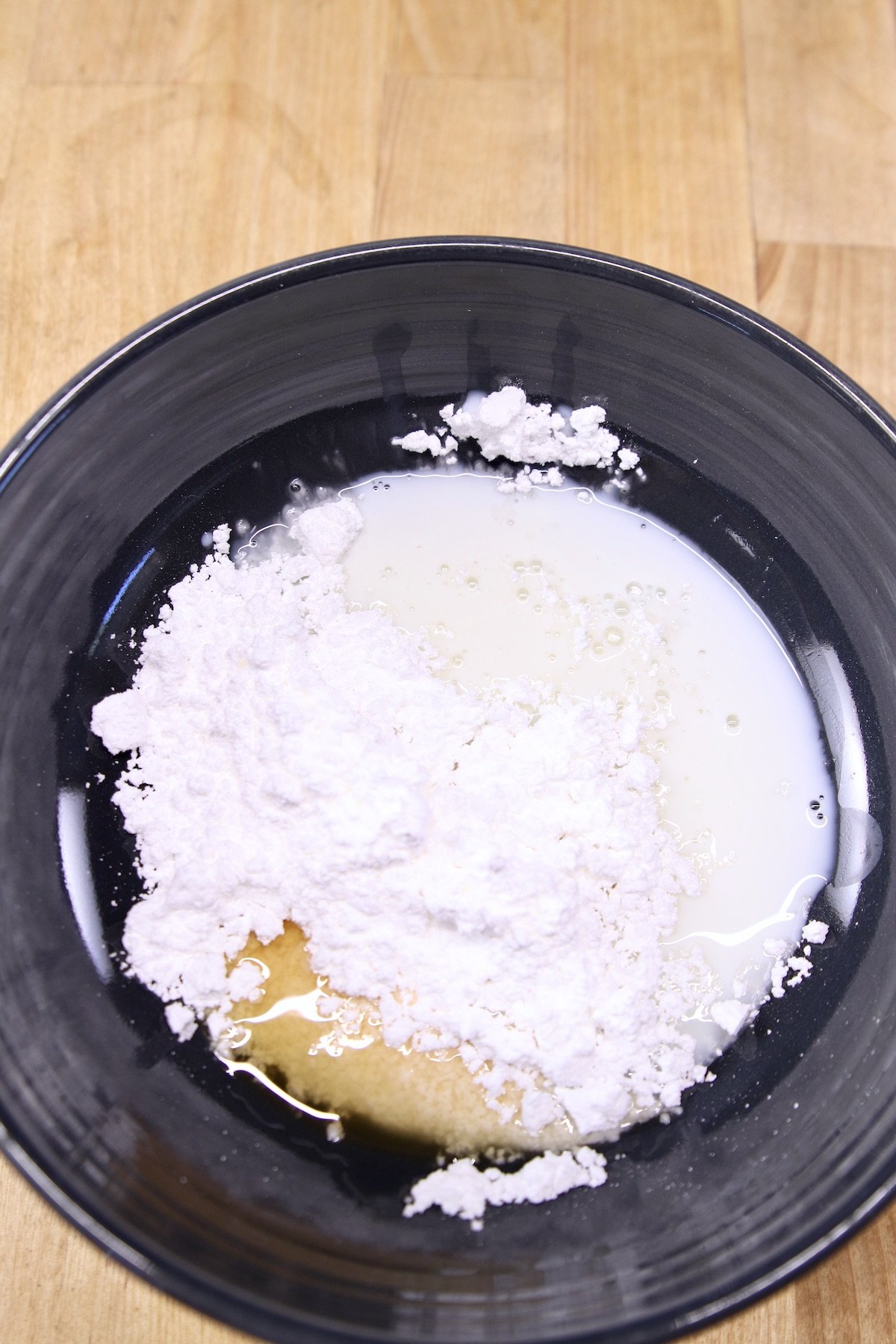 powdered sugar, milk and vanilla in a black bowl